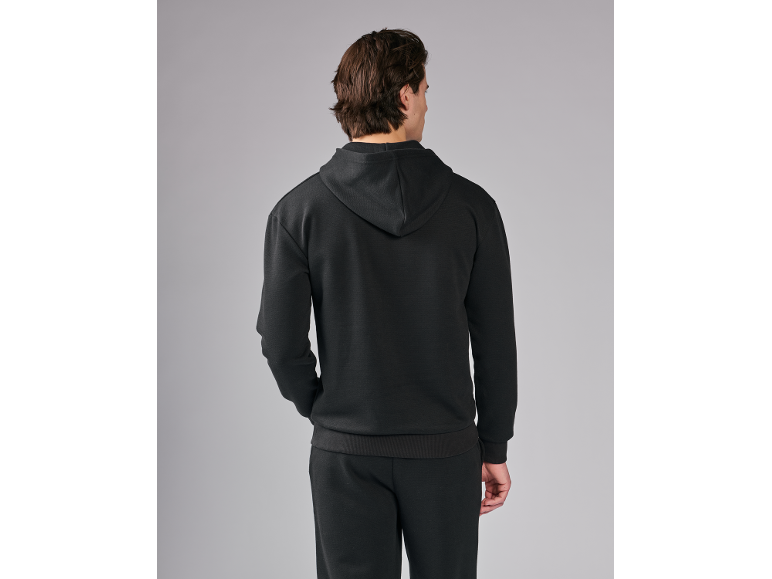 Man in zwarte hoodie en joggingbroek, achteraanzicht.
