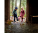 Twee kinderen in warme buitenkleding en regenlaarzen spelen in een plas.
