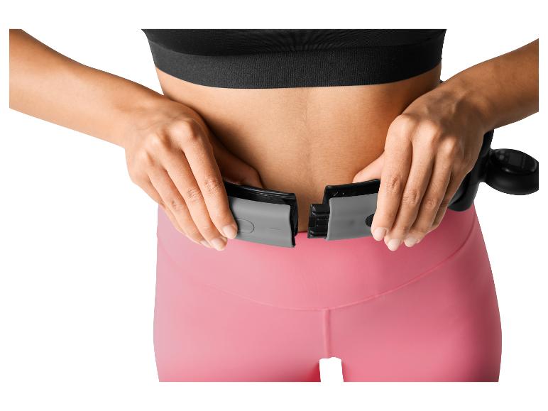 Vrouw past een slimme fitnesshoepel om haar middel aan.