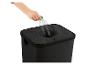 Hand plaatst een plastic fles in een zwarte wasmand met een ronde opening.