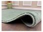 Mintgroen vloerkleed met gestikte rand op een houten vloer, met een groene vaas op de achtergrond.