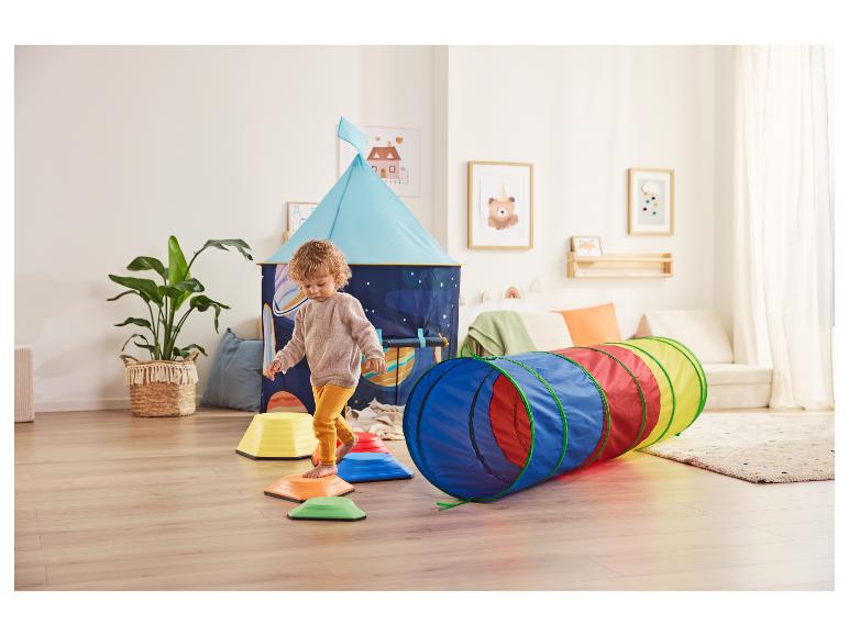 Peuter speelt op kleurrijke stapstenen en een speeltunnel in een kinderkamer met een tent.