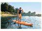 Man peddelt op een paddleboard op een meer omringd door bomen en bergen.