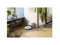 Witte robotstofzuiger op houten vloer naast laadstation in een moderne woonkamer.
