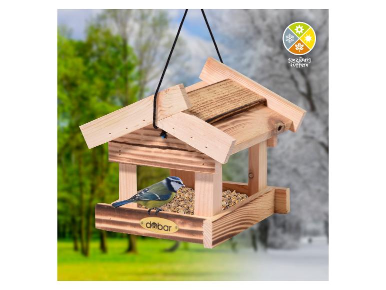 Houten vogelhuisje met een pimpelmees, tegen een achtergrond van groen en sneeuw, met seizoensicoon.