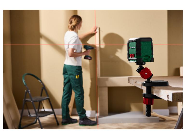 Een Parkside laserwaterpas projecteert rode lijnen op een muur terwijl een persoon werkt.