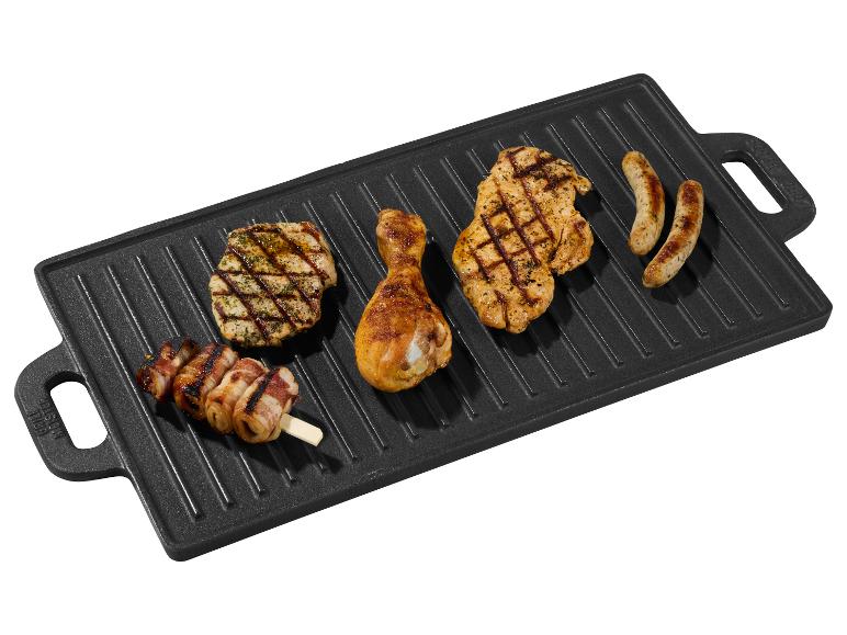 Gegrilde kip, worstjes en spekspiesjes op een gietijzeren grillplaat.