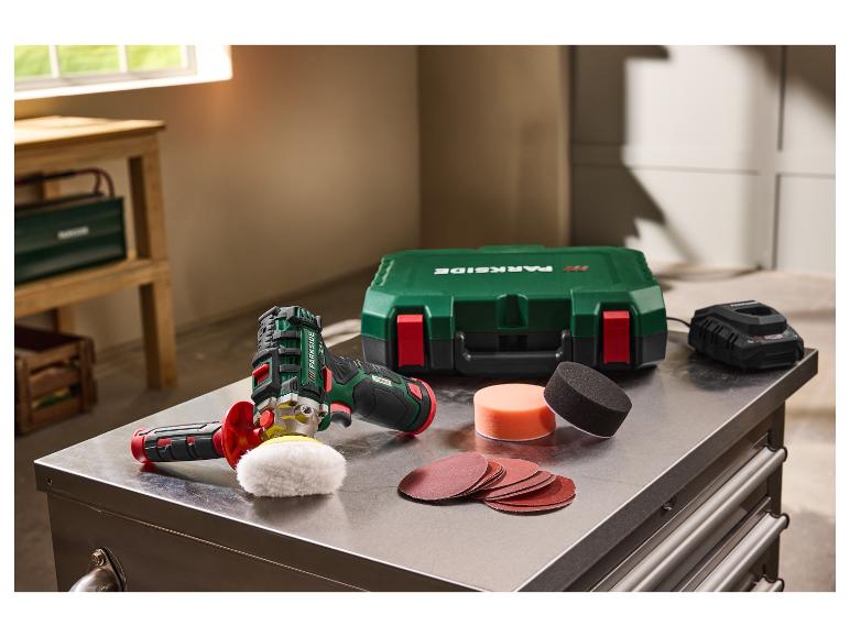 Draadloze polijstmachine met accu, oplader, koffer en accessoires op een metalen tafel.