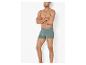 Groene herenboxershorts gedragen door een man met gekruiste armen.