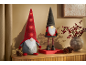 Twee feestelijke kabouters met verlichte mutsen en een vaas met rode bessen op een houten oppervlak.