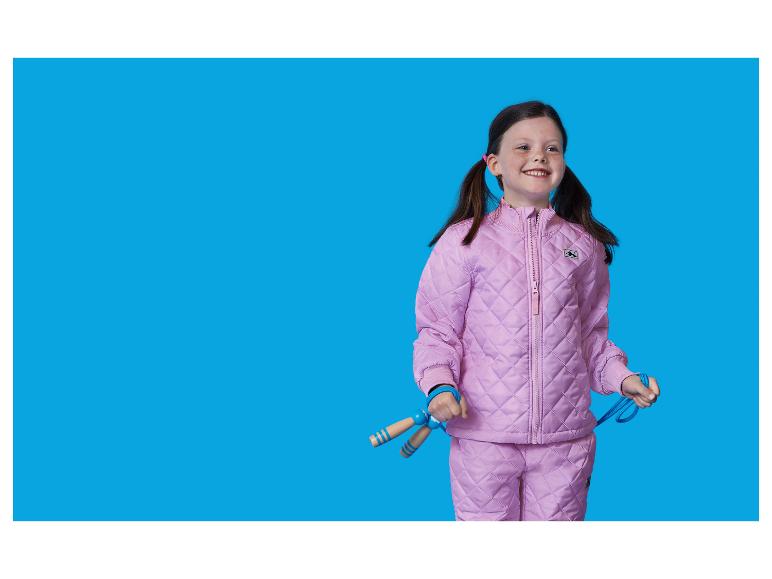 Lachend meisje in roze gewatteerd skipak, met een springtouw.
