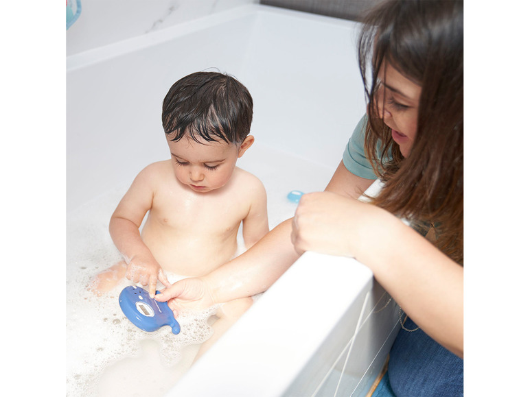 Een baby speelt met een thermometer in bad.