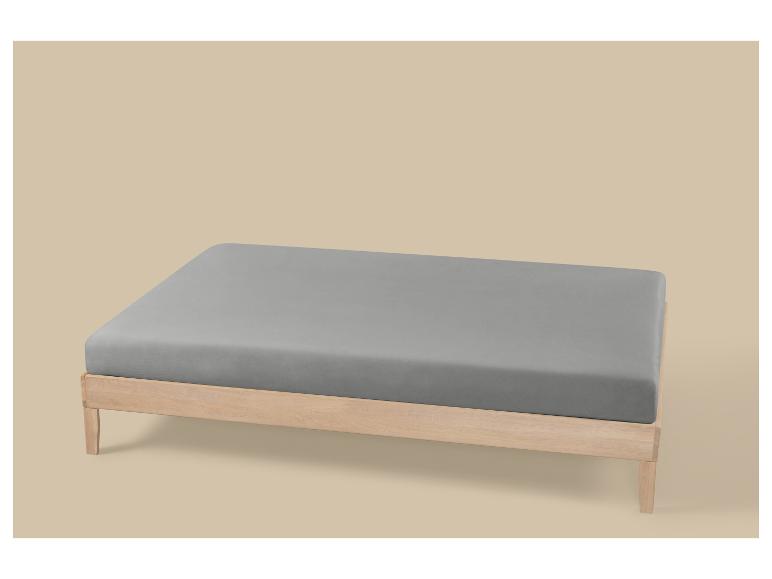 Houten bed met een grijs matras op een beige achtergrond.