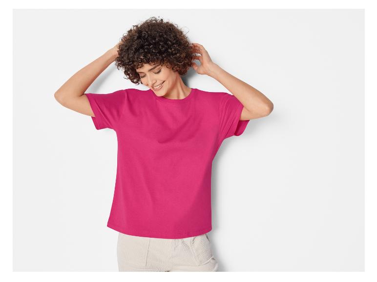 Een vrouw draagt een roze T-shirt.