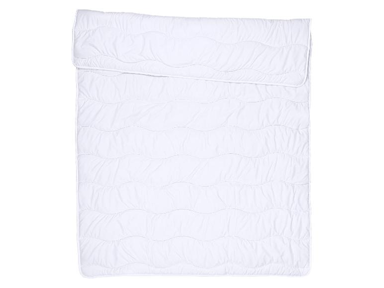 Wit gewatteerd dekbed met een golvend patroon, bovenaan gevouwen.