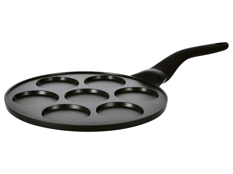 Zwarte pannenkoekenpan met zeven uitsparingen en handvat.