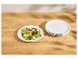Verse salade op een wit bord met een stapel borden ernaast op een houten tafel.
