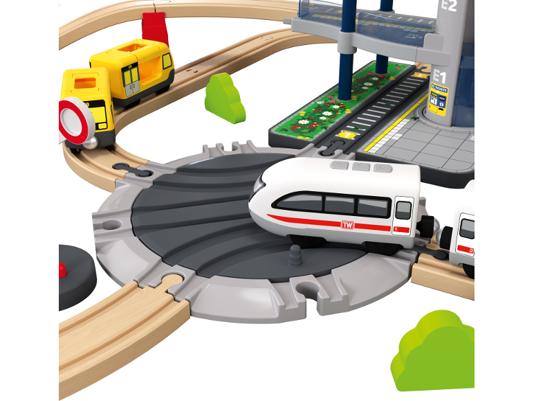 Speelgoedtreinset met gele metrotreinen, witte trein en station met meerdere verdiepingen.