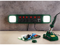 Stekkerdoos met LED-verlichting en soldeerbout op een werkbank met printplaat.
