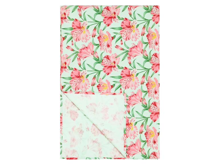 Keukenhanddoek met roze bloemen en groene bladeren op een lichtgroene achtergrond.