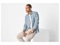 Man in blauw overhemd en beige broek, zittend op een witte kubus.