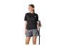 Vrouw in zwart T-shirt en grijze shorts, met wandelstokken.