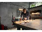 Man die een houten plank schuurt met een excentrische schuurmachine in een werkplaats.