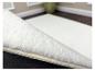 Wit pluizig tapijt met antislip onderkant, liggend op een houten vloer.