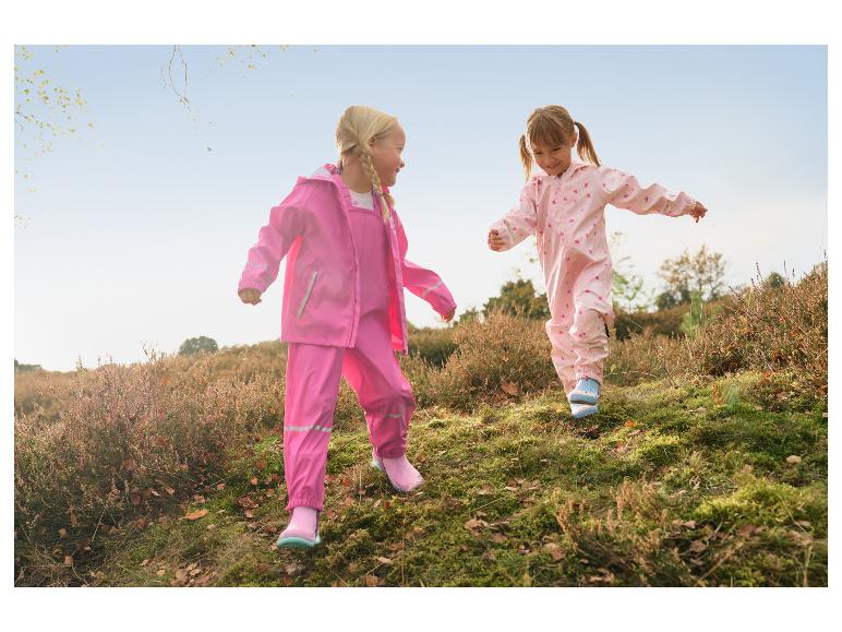Twee meisjes in roze regenpakken en regenlaarzen spelen buiten.