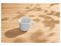 Een lege witte mok op een houten tafel met bladerschaduwen.