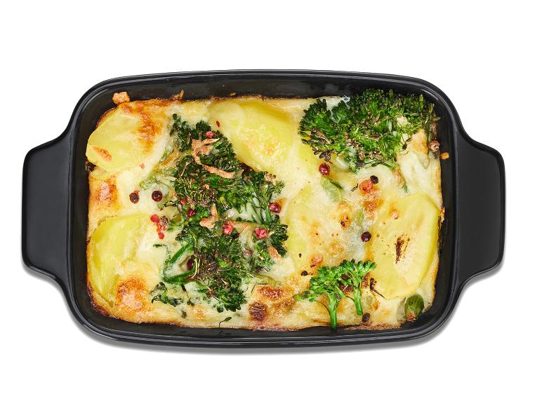 Gehaktballetjes met broccoli en aardappelpuree in een zwarte ovenschaal.