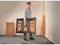Man draagt een opvouwbare werkbank in een kamer met houten planken.