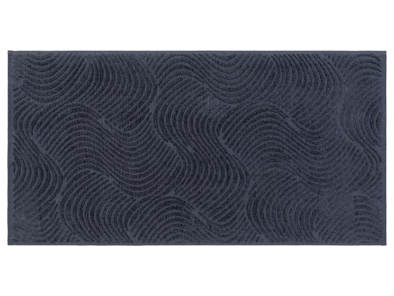 Een donkerblauw badmat met een golvend patroon.