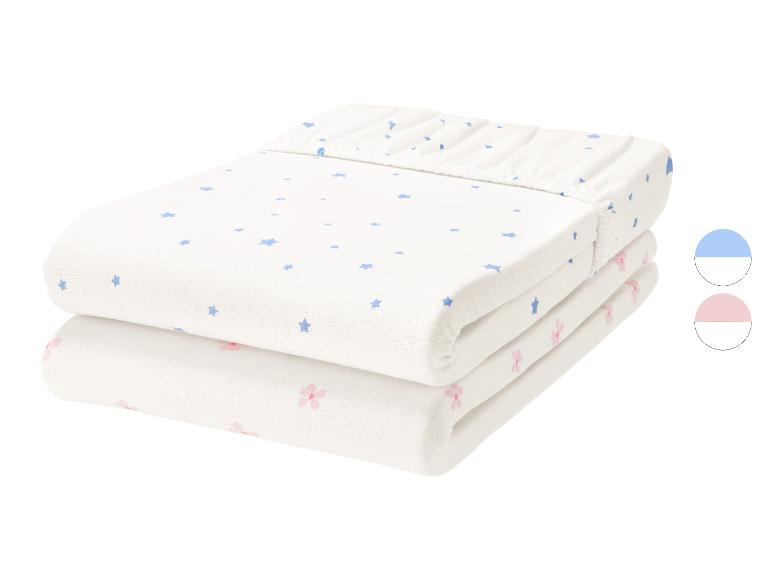 Set van 2 babyhoeslakens, één wit met blauwe sterren en één wit met roze bloemen.