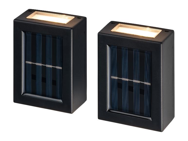 Twee zwarte, rechthoekige solar wandlampen met geïntegreerde zonnepanelen en warmwit licht.