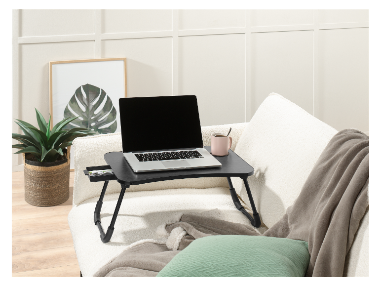 Een laptop op een opklapbare tafel op een bank.