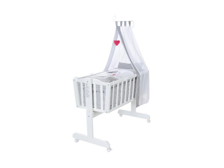 Wit babywiegje met hemel en grijs beddengoed met patroon