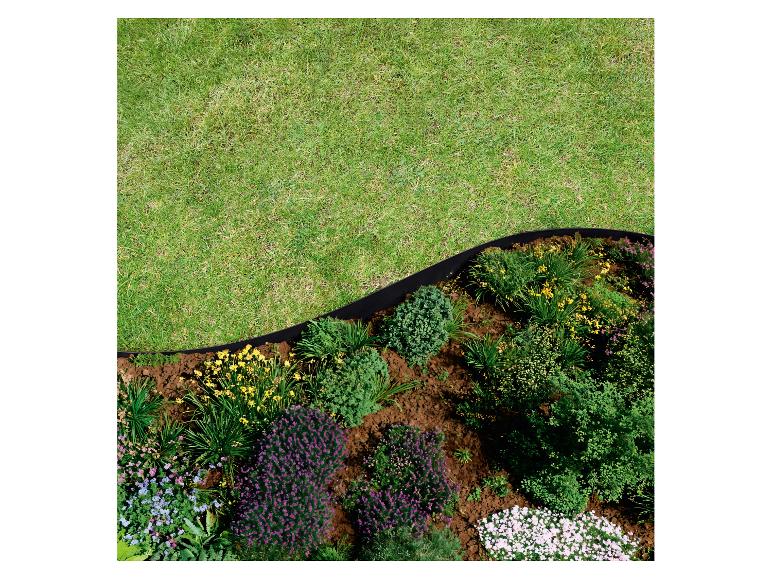 Bloembed met bloemen en struiken, gescheiden van gazon door zwarte rand