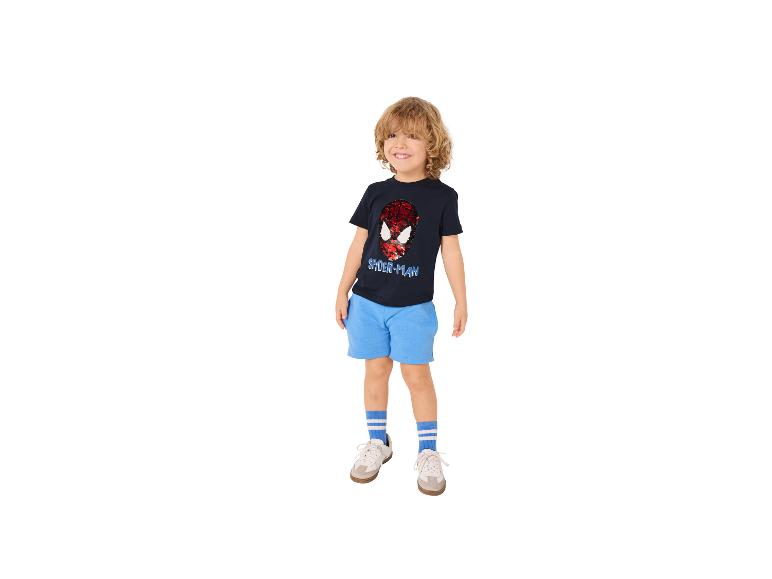 Jongen in een marineblauw T-shirt met paillettenontwerp en blauwe korte broek.