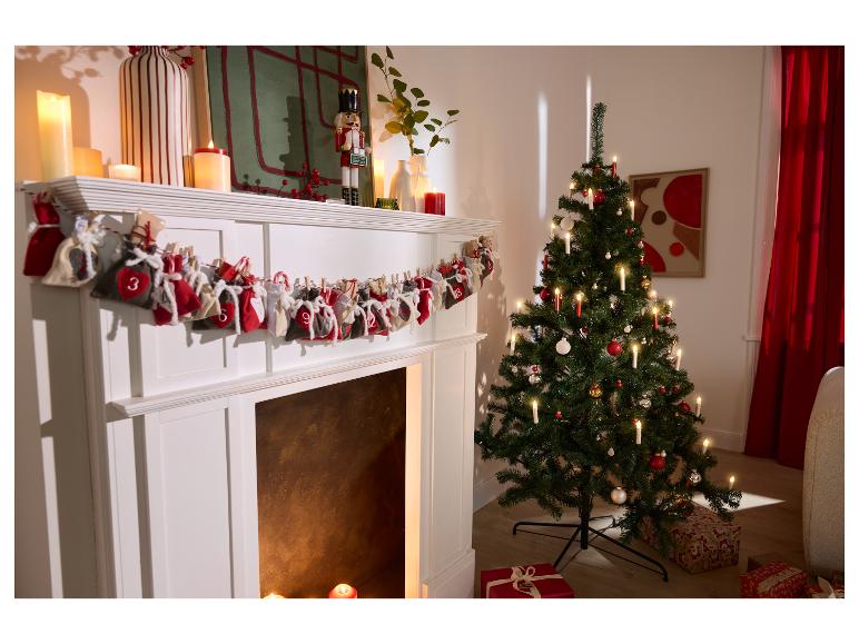 Witte open haard versierd met adventskalender en verlichte kerstboom.