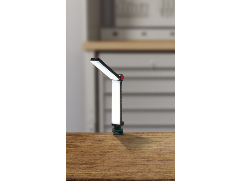 Verstelbare LED-werklamp met klem op een houten oppervlak in een werkplaatsomgeving.