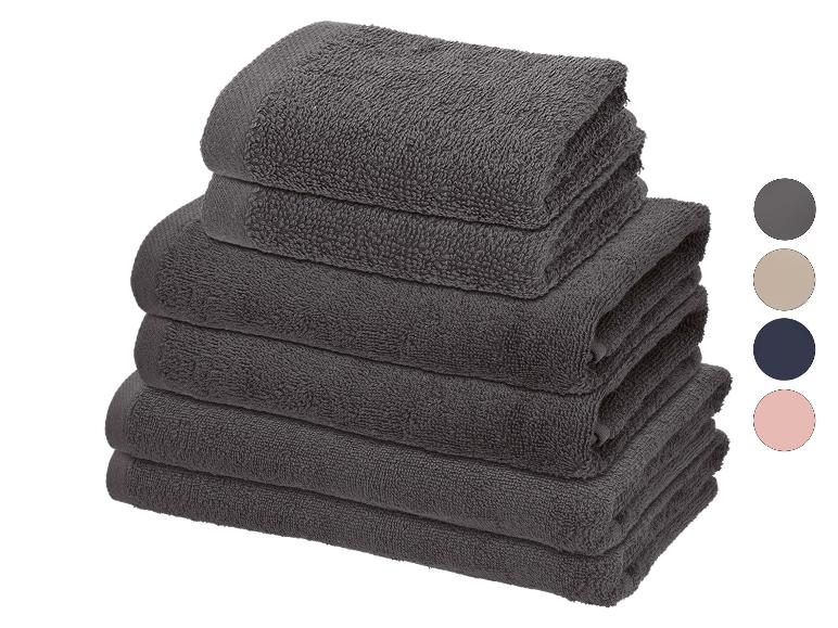 Stapel donkergrijze handdoeken met kleurstalen voor grijs, beige, marineblauw en roze.