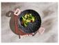 Zwarte pan met gebakken groenten (spinazie, courgette, romanesco broccoli) op een roze theedoek.