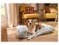 Beagle hond ligt op grijs hondenbed in woonkamer met gele meubels.