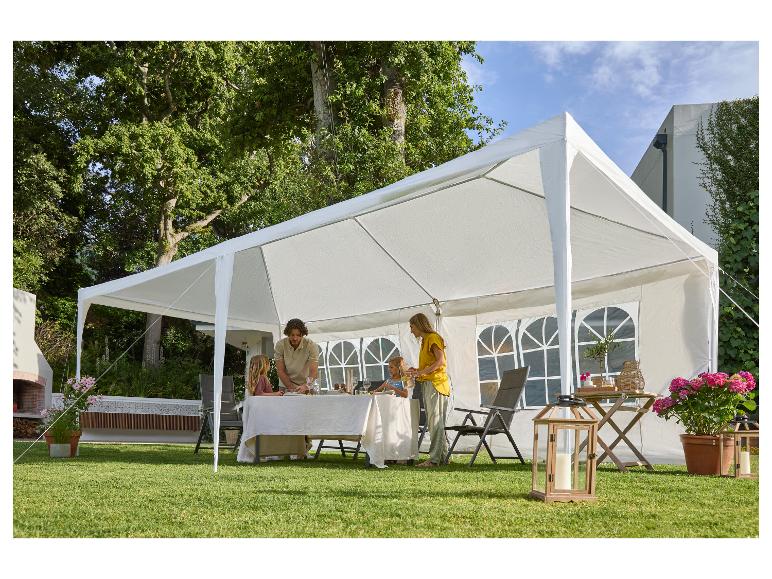 Familie onder een witte partytent in de tuin, klaar om aan tafel te eten.