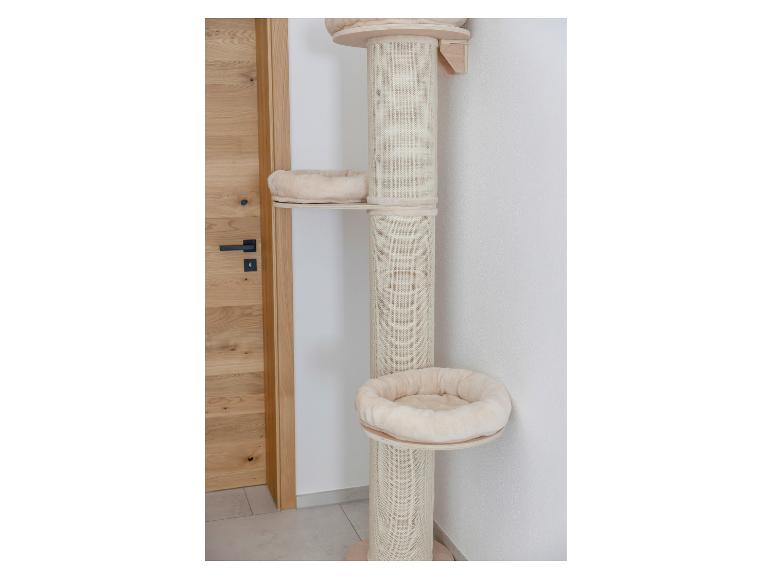 Beige krabpaal met meerdere platforms en knusse mandjes, naast een houten deur.