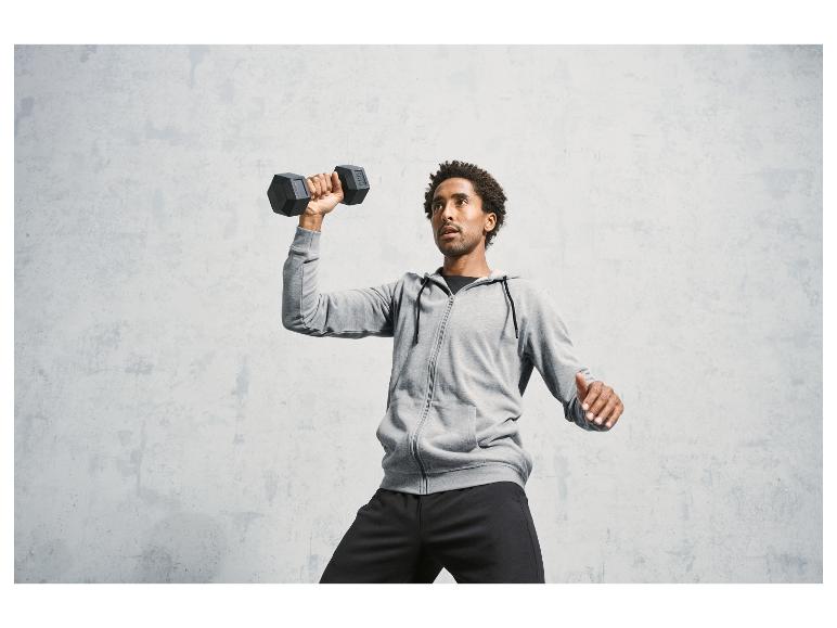 Een man in trainingspak lift een haltergewicht.
