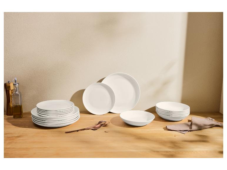 Witte serviesset op een houten tafel, met olie- en kruidenflessen.