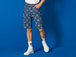 Man draagt blauwe denim shorts met Lidl-logo en witte sneakers.