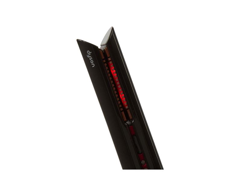 Een zwarte Dyson haarstyler met een rode lamp die aangeeft dat deze klaar is voor gebruik.